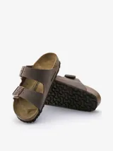 Sandalias Birkenstock modelo Arizona de color marrón con acabado tipo nubuc. Presentan un diseño de dos correas ajustables con hebillas metálicas, base anatómica de corcho y látex, plantilla de ante y suela de EVA.