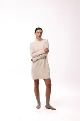 Vestido corto de tejido de punto color marrón, con cuello alto y mangas largas. Presenta un diseño de silueta relajada y terminaciones acanaladas en puños y ruedo.