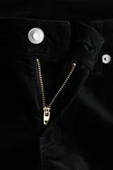 Pantalón de pana negra, corte ajustado hasta la rodilla y acampanado desde allí hasta el bajo. Tiro bajo con cierre y botón, y bolsillos abiertos delanteros y bolsillos traseros con solapa y botón.