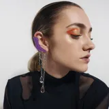 Trepadora asimétrica de acero quirúrgico plateado con pieza superior a presión y cadenas colgantes con dijes redondos y en forma de lágrima.