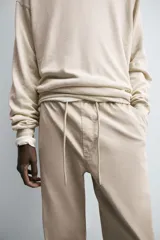 Pantalón tipo jogger de corte slim fit, confeccionado en tejido de algodón con elasticidad. Presenta cintura elástica ajustable con cordón, bolsillos frontales, bolsillos traseros de vivo y bajos con puños elásticos.