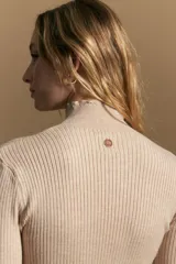 Polera de tejido acanalado con cuello alto, corte ajustado al cuerpo y mangas tres cuartos con terminaciones onduladas en los puños.