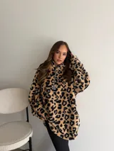 Buzo de peluche con estampado animal print de leopardo, cuello alto con cierre frontal parcial y tirador metálico decorativo.