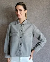 Sobrecamisa gris de denim con cuello clásico, cierre frontal con botones a presión, dos bolsillos de parche con solapa en el pecho y mangas largas con puños abotonados.