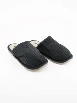 Pantufla abierta de diseño acanalado en color negro, con interior forrado en material sintético de textura suave y suela de goma.