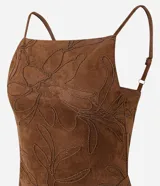 Vestido midi de gamuza sintética color marrón, con diseño de bordado de follaje en relieve. Presenta escote recto, tirantes finos regulables, ajuste al cuerpo, espalda con lastex y abertura frontal en la falda.