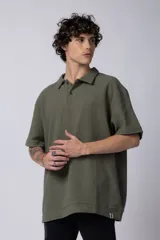 Chomba de manga corta con cuello polo, confeccionada en tejido de punto acanalado de textura pesada. Presenta un calce relajado y cuenta con una pequeña etiqueta distintiva en el ruedo.