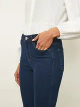 Jean de corte skinny en color azul medio, con tiro medio, cierre frontal con botón y bolsillos laterales y traseros.