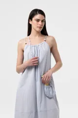Vestido midi celeste de calce amplio y liviano, con escote fruncido regulable y breteles finos con detalles de cuentas. Presenta una silueta suelta e incluye una mini cartera desmontable al tono.