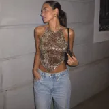 Top halter con lentejuelas en tonos dorados y marrones, con diseño en punta en el dobladillo inferior y tirantes regulables para atar al cuello y la espalda.