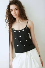 Top negro de jersey con tirantes finos y escote redondo, decorado con apliques circulares de nácar distribuidos por toda la prenda.