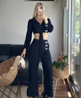 Conjunto color beige compuesto por un top corto con escote en V, botones frontales y mangas largas abullonadas con puños elásticos, y un pantalón de tiro alto con lazo en la cintura.