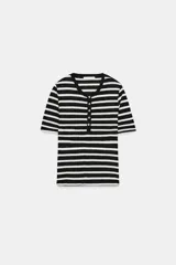 Camiseta de manga corta con diseño a rayas horizontales en blanco y negro, cuello redondo y cartera con botones frontales.