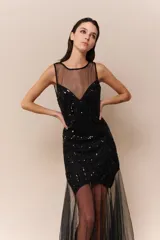 Vestido midi negro con cuerpo bordado en lentejuelas y canutillos, escote redondo y falda con superposición de tul transparente. Presenta espalda descubierta y cierre invisible.