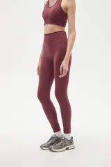 Calza deportiva de tiro alto y ajuste ceñido al cuerpo, confeccionada en tejido elástico de color bordó.