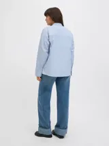 Camisa de popelín blanca de manga larga con cuello clásico y cierre frontal de botones ocultos, de ajuste relajado y puños anchos.