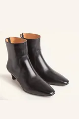 Botín blanco con estampado de piel de serpiente, punta fina y taco chupete. Cierre con cremallera en la parte trasera.