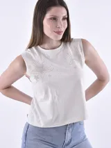 Musculosa color crema con cuello redondo y sisas pronunciadas. Presenta un estampado de estrellas grandes y pequeñas hechas con apliques brillantes en la parte frontal.