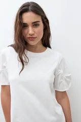Remera negra de algodón con cuello redondo y mangas cortas abullonadas con detalle de frunces.