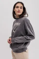 Buzo gris de felpa oversize con estampado frontal de mariposa y texto.