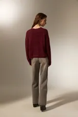 Sweater de punto negro con destellos de lurex, cuello redondo a la base y mangas largas con puños ajustados.