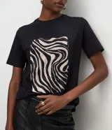 Remera de algodón color negro con cuello redondo y mangas cortas. Presenta una estampa frontal abstracta con líneas onduladas en tonos claros.