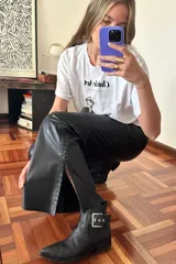 Pantalón Oxford de cuero negro con cierre frontal y pasamanería plateada en los tajos laterales.