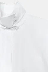 Camisa blanca de algodón de la colección ZW Collection de Zara, con cuello alto, mangas abullonadas por debajo del codo y cierre frontal con botones ocultos por solapa.