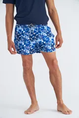 Short de baño con estampado floral en tonos azules y detalles en naranja, con cintura elástica y cordón ajustable.