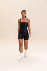Jumpsuit corto de diseño ajustado con escote cuadrado y breteles finos. Confeccionado en tejido técnico con acabado ligeramente brillante y textura acanalada, ofrece compresión media y alta elasticidad.