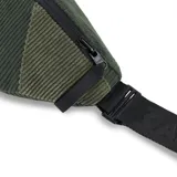 Riñonera verde de pana con correa ajustable negra y logo de la marca en cuero sintético. Reversible, con cierre YKK y compartimento principal con bolsillo lateral. Se puede usar en la cintura o al hombro.