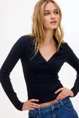 Top de manga larga color negro, confeccionado en tejido de punto acanalado, con cuello camisero y abertura frontal en V.