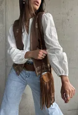 Blusa blanca de mangas largas abullonadas con puños elásticos y detalles de encaje y bordados sutiles. Presenta escote en V con tiras decorativas y diseño holgado.