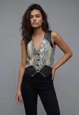 Chaleco ajustado con escote en V, cierre frontal con botones y detalles de tachas doradas. El cuerpo principal presenta un estampado de piel de serpiente en tonos beige y azul verdoso, contrastado con paneles de cuero negro en los hombros y el bajo.