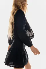 Pollera corta acampanada negra de algodón, con detalles de pinzas y paneles de encaje en el frente y laterales. Presenta un ruedo con terminación de encaje festoneado.