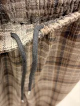 Pantalón tipo balloon de tejido plano con calce relajado, cintura elastizada y estampado cuadrillé en tonos marrones y beige.