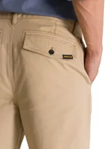 Pantalón chino Caterpillar de corte tapered straight, color beige, con tiro medio, bragueta con cremallera y botón, bolsillos laterales y bolsillos traseros con solapa y botón.