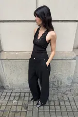 Camiseta negra de corte ajustado (slim fit) con escote pico y manga sisa. Presenta una aplicación de encaje a tono en el escote.