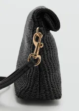 Bolso de mano mediano color negro, confeccionado con tejido trenzado tipo rafia. Cuenta con solapa frontal con cierre de botón a presión metálico dorado, asa de muñeca desmontable y detalle de logo grabado en dorado.