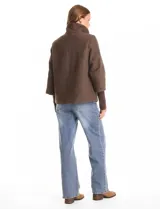 Tapado de tejido bouclé color marrón, con silueta evasé y largo a la cadera. Presenta cuello alto envolvente, cierre frontal oculto con botones a presión y bolsillos frontales de gran tamaño. Sus mangas son 3/4 con corte amplio y puños de tejido rib al tono que se extienden para cubrir las muñecas.