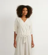 Blusa color crema con estampado animal print de jaguar en tonos dorados, escote en V, mangas 3/4 y nudo en la parte inferior.