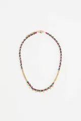 Collar corto con cuentas de metal dorado y cuentas de vidrio azul oscuro, con detalles de pequeñas borlas doradas en la parte frontal.