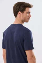 Remera azul marino de manga corta con cuello redondo, confeccionada en mezcla de algodón y poliéster. Presenta un diseño en el frente que combina estampa y bordado con la leyenda "Legacy Brand 1972" en tonos rosado, verde y marrón.