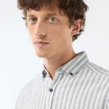 Camisa de manga larga confeccionada en mezcla de lino y algodón, con diseño de rayas verticales en tonos verde y blanco, cuello abotonado y cierre frontal de botones.