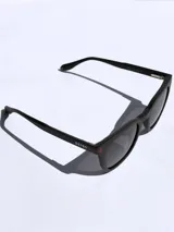 Lentes de sol Osten modelo Tokyo, con armazón de acetato negro y diseño clásico. Presentan detalles en rojo en las patillas y cristales oscuros con protección UV.