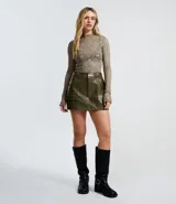 Short pollera de tiro medio confeccionado en poliuretano color verde oliva, con diseño de bolsillos frontales con solapa y cierre mediante cremallera.