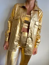 Camisa dorada brillante con cuello clásico, cierre frontal con botones y bolsillos de parche en el pecho.