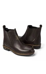 Bota tipo chelsea de gamuza color tostado, con elásticos laterales y suela de goma con detalle de logo metálico en el talón.