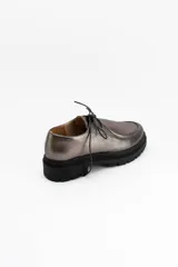 Zapatos tipo wallabee de cuero metalizado en tono peltre, con cordones negros y suela track de goma negra con plataforma.