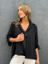 Camisa oversize color negro, con cuello camisero, cierre frontal con botones y mangas largas con presillas para arremangar.